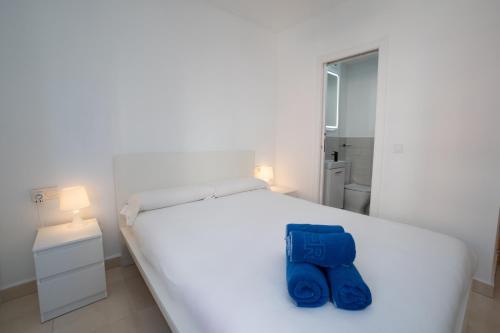 Un dormitorio con una cama blanca con toallas azules. en NEPTUNO 2C MENYBER, en Nerja
