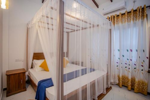 a bedroom with a canopy bed and a window at Eleena House in Galle
