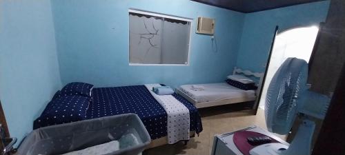 a small blue room with a bed and a window at CASA DE HOSPEDAGEM PARATY 10 MINUTOS DO CENTRO COM OPÇÕES DE CAFÉ da MANHÃ in Paraty