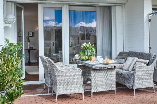 a patio with a table and chairs on a porch at Techts Apartmenthaus in Timmendorfer Strand
