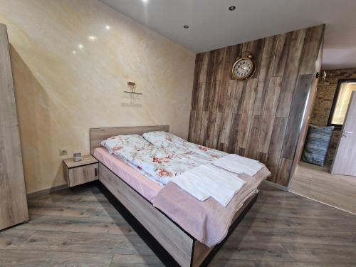 a bedroom with a bed and a clock on the wall at Black Swan guest rooms in Mechkarevo