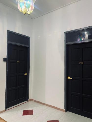 two black doors in the corner of a room at Casaria Inn Paka in Paka