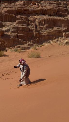 a person kneeling in the sand in the desert at Syndebad desert camp in Wadi Rum