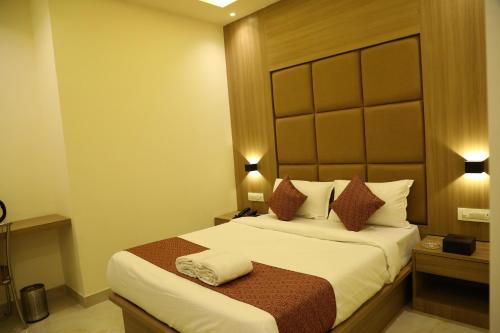 a hotel room with a bed with white sheets and pillows at Hotel Bellamont in Mumbai