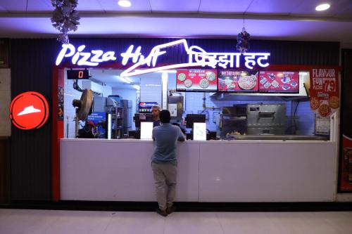 a man standing at the counter of a pizza restaurant at Hotel Bellamont in Mumbai