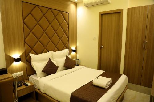 a hotel room with a large bed with a large headboard at Hotel Bellamont in Mumbai
