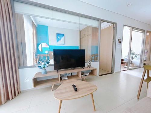a living room with a television and a table with a stool at The Sóng Vũng Tàu Hideaway in Vung Tau