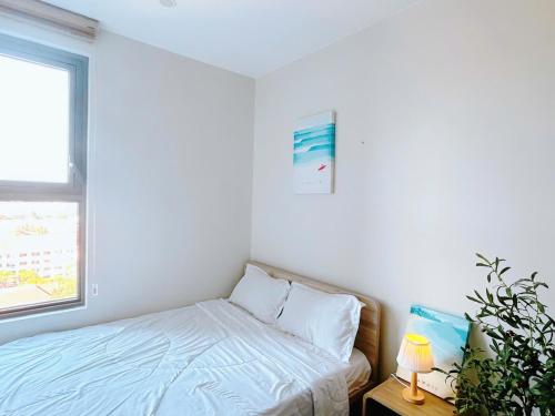 a white bedroom with a bed and a window at The Sóng Vũng Tàu Hideaway in Vung Tau