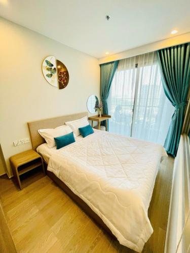 a bedroom with a large white bed with blue pillows at The Sóng Vũng Tàu Hideaway in Vung Tau