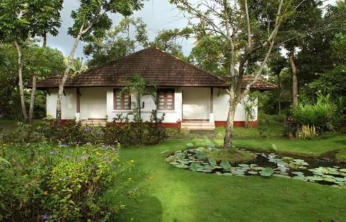a house with a garden and a pond in front of it at Abad Turtle Beach in Mararikulam