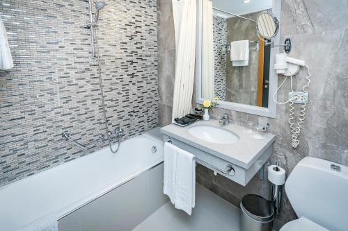 a bathroom with a sink and a tub and a toilet and a mirror at Tirana International Hotel & Conference Center in Tirana