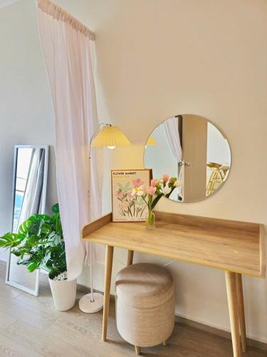 a table with a mirror and a vase of flowers on it at The Sóng Vũng Tàu Hideaway in Vung Tau