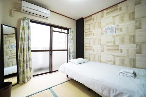 a bedroom with a bed and a window at Charade Kyobashi in Osaka