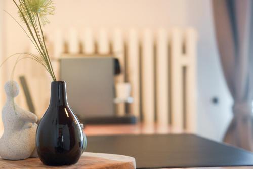 a black vase sitting on a table with a plant at Hotel Garni in der Breite in Albstadt