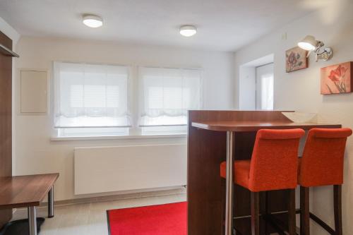 a kitchen with a bar with two orange chairs at Hotel Garni in der Breite in Albstadt