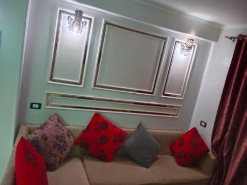 sala de estar con sofá y almohadas rojas en الشريف للشقق الفندقيه, en Abu Simbel