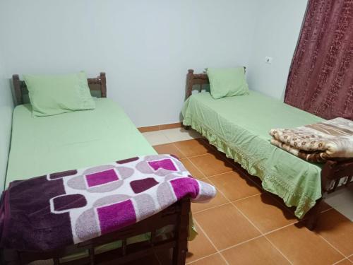 Habitación con 2 camas y mantas verdes y moradas. en الشريف للشقق الفندقيه, en Abu Simbel