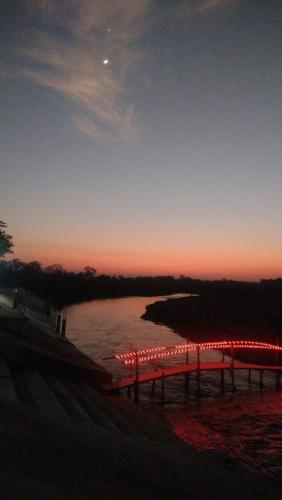 a sunset over a body of water with a pier at Amantran Hotel & Resort, Chilapata in Patkapāra