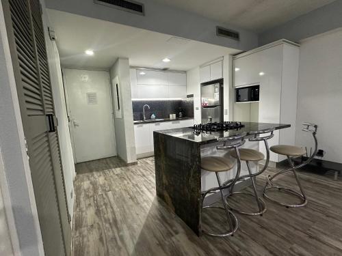 a kitchen with a counter and two bar stools at Apto Vip acceso a la playa in El Morro de Barcelona