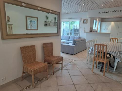 - un salon avec une table, des chaises et un miroir dans l'établissement Maison bord de mer pour 9 pers. avec terrasse, BBQ, WiFi - à 300m de la plage, tout confort - FR-1-323-501, à Saint-Hilaire-de-Riez