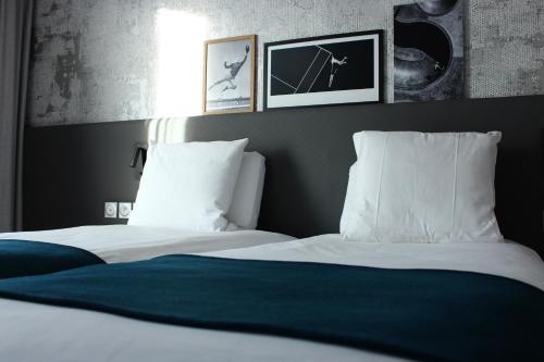 a bedroom with two white beds and pictures on the wall at BEST WESTERN HOTEL DIJON QUETIGNY in Quétigny