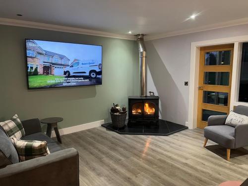 a living room with a fireplace and a tv on the wall at Gellyburn Cottage in Kinross