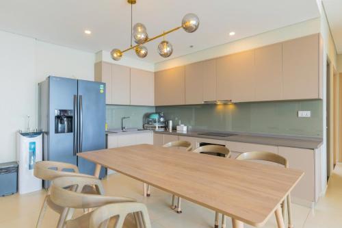 a kitchen with a wooden table and a blue refrigerator at The Sóng Vũng Tàu Hideaway in Vung Tau