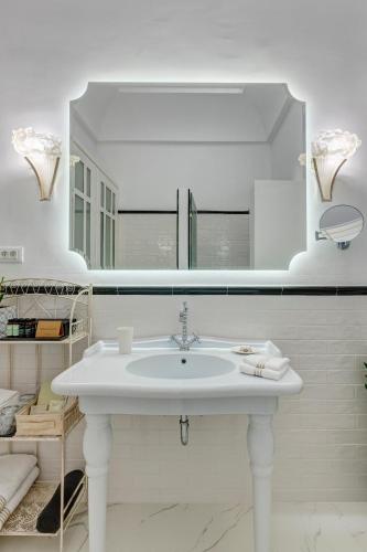 a white bathroom with a sink and a mirror at Palazzo Santa Maria - Historic Hotels of Europe in Ermoupoli