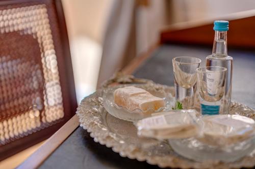 a glass plate with food and a bottle on a table at Palazzo Santa Maria - Historic Hotels of Europe in Ermoupoli