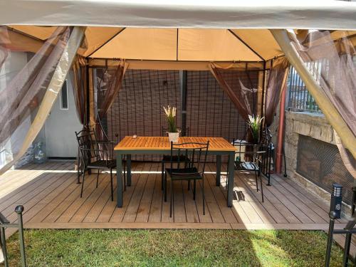 a wooden deck with a table and chairs under a tent at Gatto Matto in Brolo
