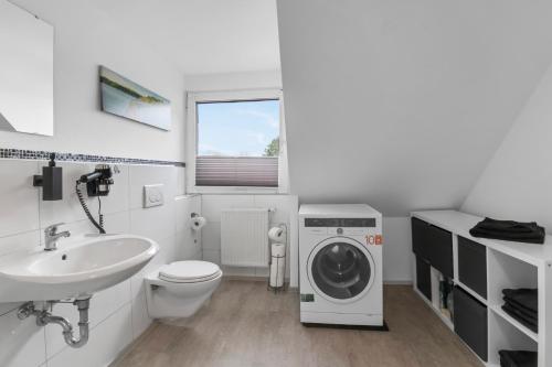a bathroom with a washing machine and a sink at 24-7 Living - Unna Central City Apartments in Unna
