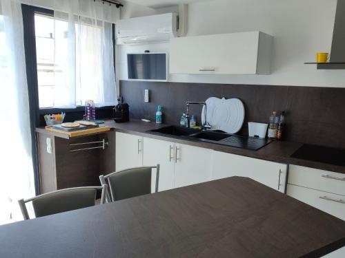 une cuisine avec des armoires blanches et un comptoir noir dans l'établissement Studio Cabine Climatisé à 150m de la Mer - Parking Privatif - Animaux Acceptés - FR-1-776-100, à Saint-Cyprien