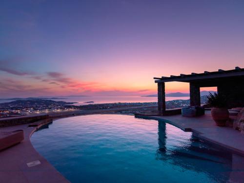 a swimming pool with a sunset in the background at Mykonos Rocks Villas & Suites in Mýkonos City