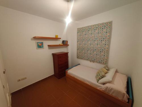a small bedroom with a small bed and a wall at La casa del verano in Isla Cristina