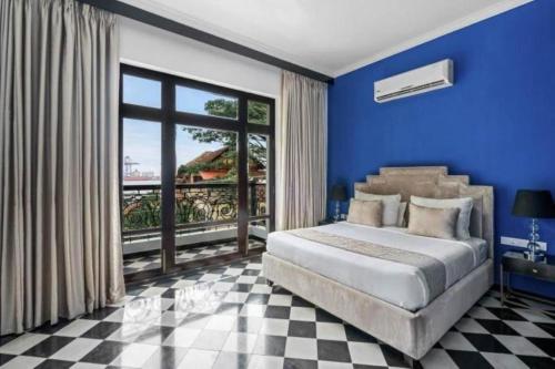 a blue bedroom with a bed and a large window at The Old Court House By Abad in Cochin