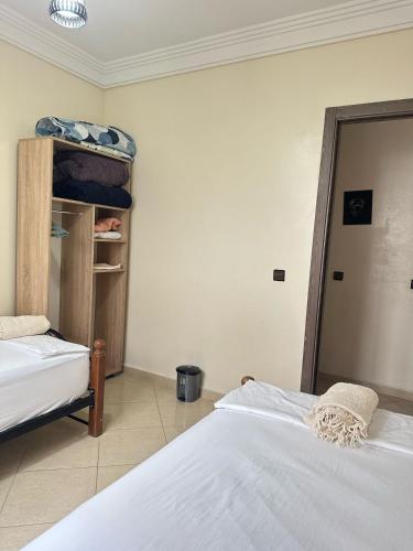 a bedroom with two beds and a shelf with towels at Charming Room Near Marrakech Airport in Marrakech