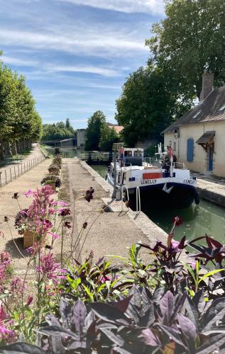 a boat is docked in a canal with flowers at La maison Virginie 1 à 2 pers charmant central-parking gratuit- linge- fibre- proximité port lac canal piscine in Montargis