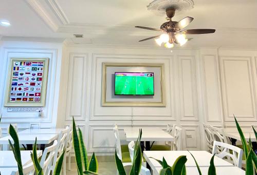 a dining room with white tables and a ceiling fan at Hotel La Perle in Hue