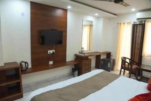 a bedroom with a bed and a tv on the wall at Hotel Om Regency in Ghaziabad