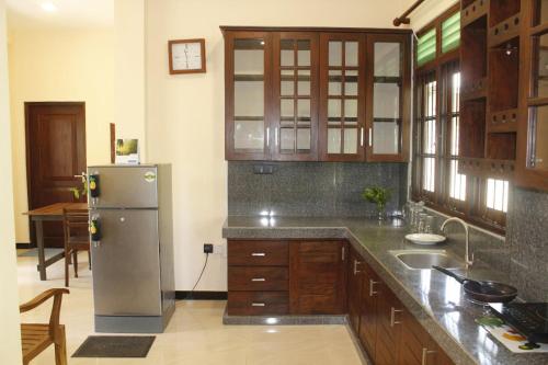 a kitchen with a stainless steel refrigerator and wooden cabinets at Cinnamon Edge in Mihiripenne