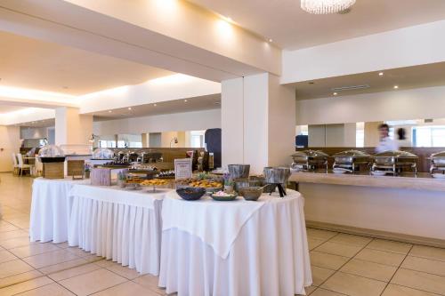 a buffet line with white tables in a restaurant at Ariti Grand Hotel in Corfu Town
