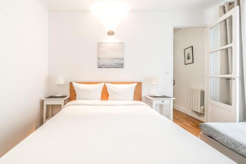 a white bedroom with a large bed and two tables at Levis Charming Place in Paris