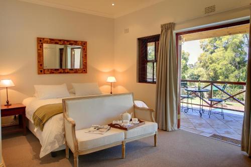 L'Heritage Retreat في Wildernis: غرفة نوم بسرير وطاولة وبلكونة