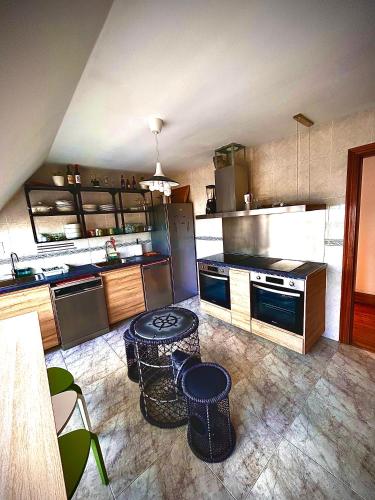 a large kitchen with stainless steel appliances and tables at EL TRASTERO DE PALMERO in A Coruña