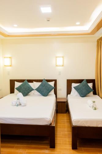 two beds in a room with white sheets and blue pillows at Anahaw Seaside Inn in Bantayan Island