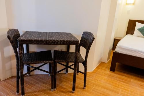 a small table and chairs in a room with a bed at Anahaw Seaside Inn in Bantayan Island