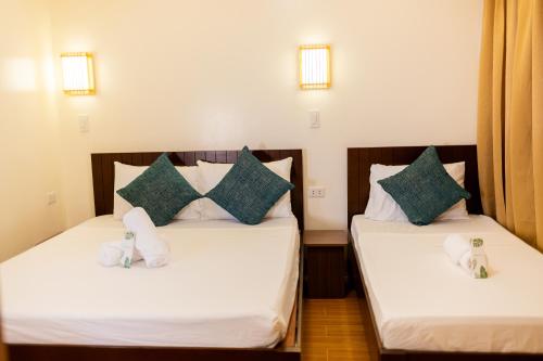 two beds in a room with towels on them at Anahaw Seaside Inn in Bantayan Island