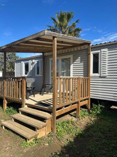 a house with a wooden deck with a pergola at MOBIL HOME Le Soleil,3CH,6PERS in Port-la-Nouvelle
