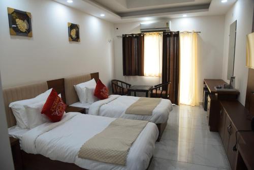 a hotel room with two beds and a desk at Hotel Om Regency in Ghaziabad