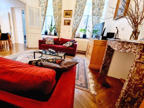 un salon avec des meubles rouges et une cheminée dans l'établissement Gîte paisible avec jardin privatif et terrasse, 2 chambres, proche sites culturels, animaux acceptés - FR-1-510-174, à Romeries